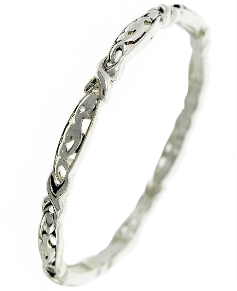 Puede incluir: Un brazalete de plata con un delicado dise&ntilde;o intrincado de hojas y vides en espiral.