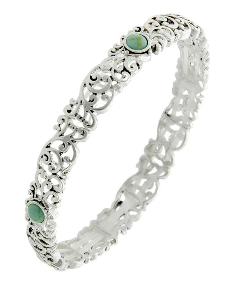 May include: Silver bangle bracelet with an openwork filigree design. The bracelet has two oval turquoise-coloured stones. The intricate metalwork creates a delicate and ornate appearance, suitable for adding a touch of elegance to any outfit.