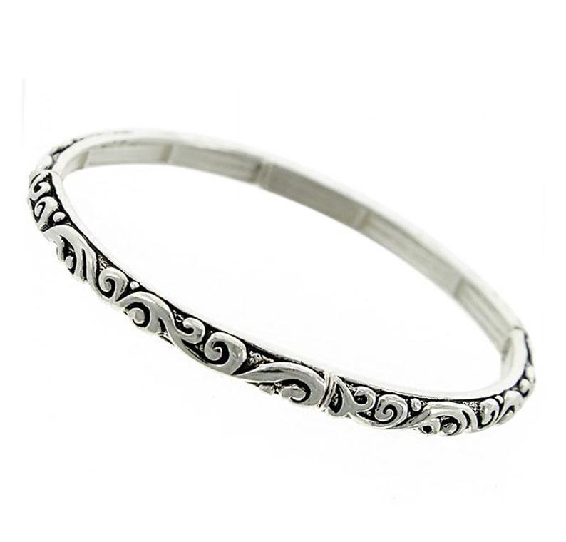 Puede incluir: Un brazalete de plata con un dise&ntilde;o decorativo de espirales.