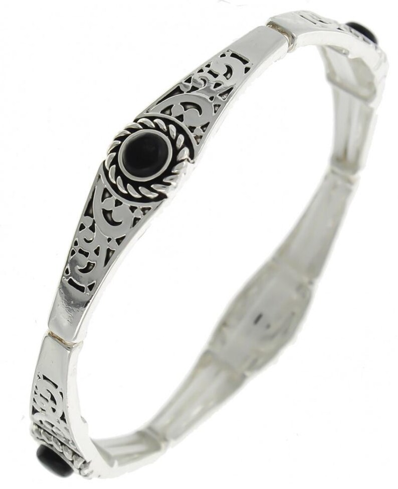 May include: A silver bracelet featuring an intricate design and black stones. The bracelet is expandable and has a delicate, feminine look.