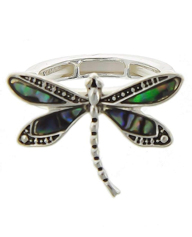 May include: A silver ring with a dragonfly design. The dragonfly's wings are made of abalone shell and have a green, blue, and black iridescent sheen. The dragonfly's body is silver and has black accents.