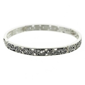 May include: A silver bangle bracelet with an intricate floral design. The bracelet is made of metal and has a delicate, feminine look.