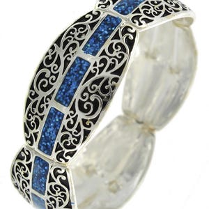 Pu&ograve; includere: Bracciale argentato con filigrana nera e inserti rettangolari blu glitterati. Il bracciale ha un design ornato con una fascia elastica. Un accessorio di moda.