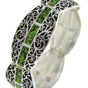Pu&ograve; includere: Bracciale argentato con filigrana nera e inserti rettangolari di glitter verde. Il bracciale ha un design articolato, che consente flessibilit&agrave; e comfort. L'intricato traforo e i vivaci accenti verdi creano un contrasto sorprendente.