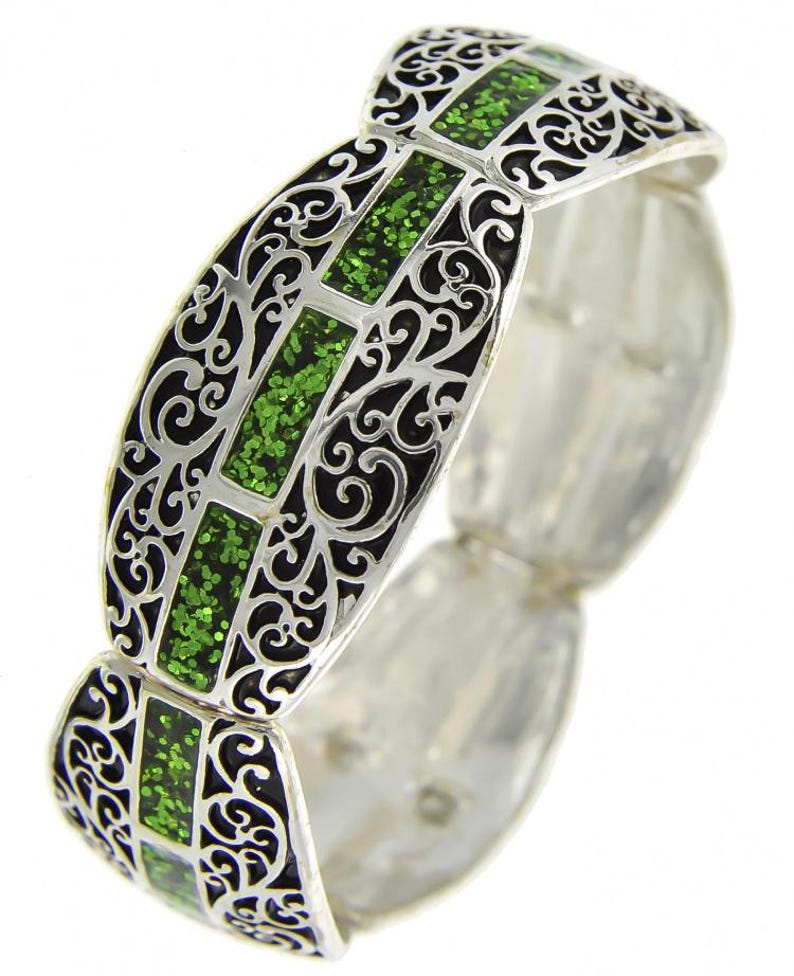 Pu&ograve; includere: Bracciale argentato con filigrana nera e inserti rettangolari di glitter verde. Il bracciale ha un design articolato, che consente flessibilit&agrave; e comfort. L'intricato traforo e i vivaci accenti verdi creano un contrasto sorprendente.