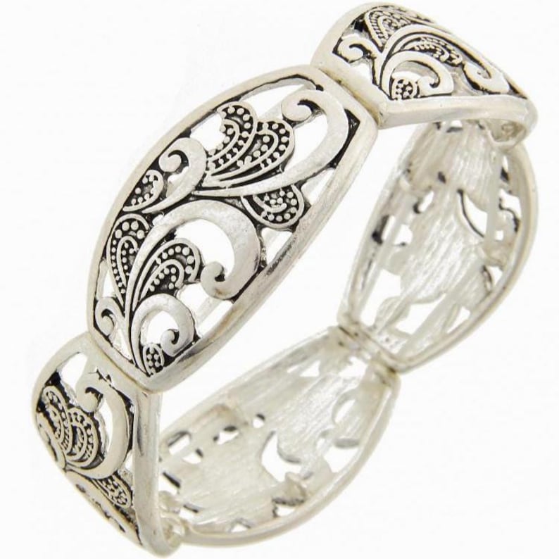 以下が含まれることがあります： シルバーカラーのストレッチブレスレット、オープンワークデザイン。 ブレスレットは、渦巻く線と花のモチーフの複雑なパターンが特徴です。 ブレスレットは金属製で、アンティーク仕上げです。