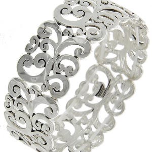 Może przedstawiać: Srebrna bransoletka typu bangle z delikatnym, skomplikowanym wzorem wirujących, kwiatowych wzor&oacute;w. Bransoletka jest otwarta i ma lekko młotkowaną fakturę.