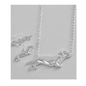 May include: Silver dachshund necklace and earrings set. The necklace features a dachshund pendant with a silver chain. The earrings are silver dachshund studs.