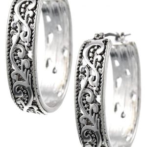 May include: A pair of silver-toned hoop earrings. Each earring features an intricate, openwork filigree design along the outer edge. The hoops have a slightly flattened, oval shape and a secure clasp closure. The earrings are designed for pierced ears.