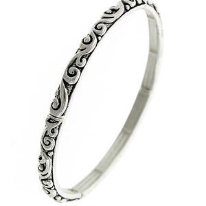 Puede incluir: Un brazalete de plata con un patr&oacute;n decorativo de espiral.