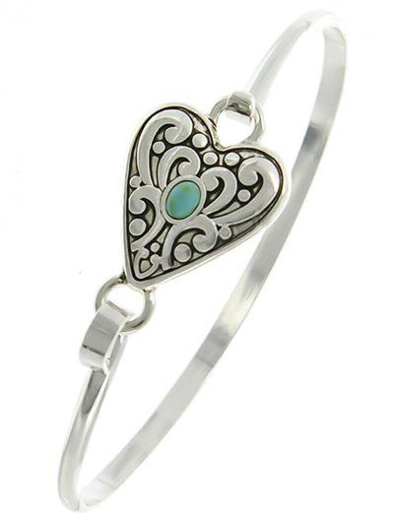 Peut inclure: Un bracelet jonc en argent avec un pendentif en forme de c&oelig;ur. Le pendentif est d&eacute;cor&eacute; d'un motif de filigrane et pr&eacute;sente une pierre turquoise au centre.