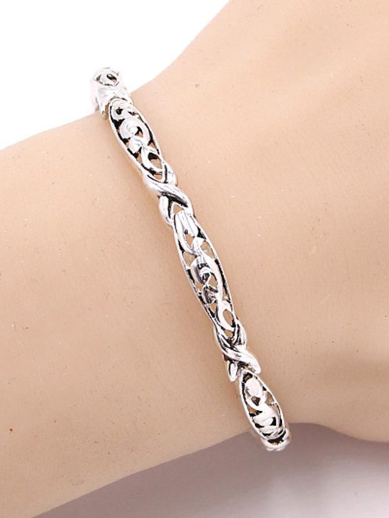 Puede incluir: Pulsera de plata con un dise&ntilde;o delicado e intrincado. La pulsera est&aacute; hecha de una cadena retorcida y calada con un patr&oacute;n floral.