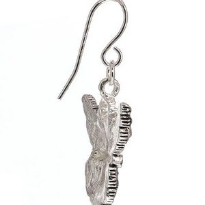 May include: Silver butterfly dangle earrings with a textured design. The earrings have a hook closure.