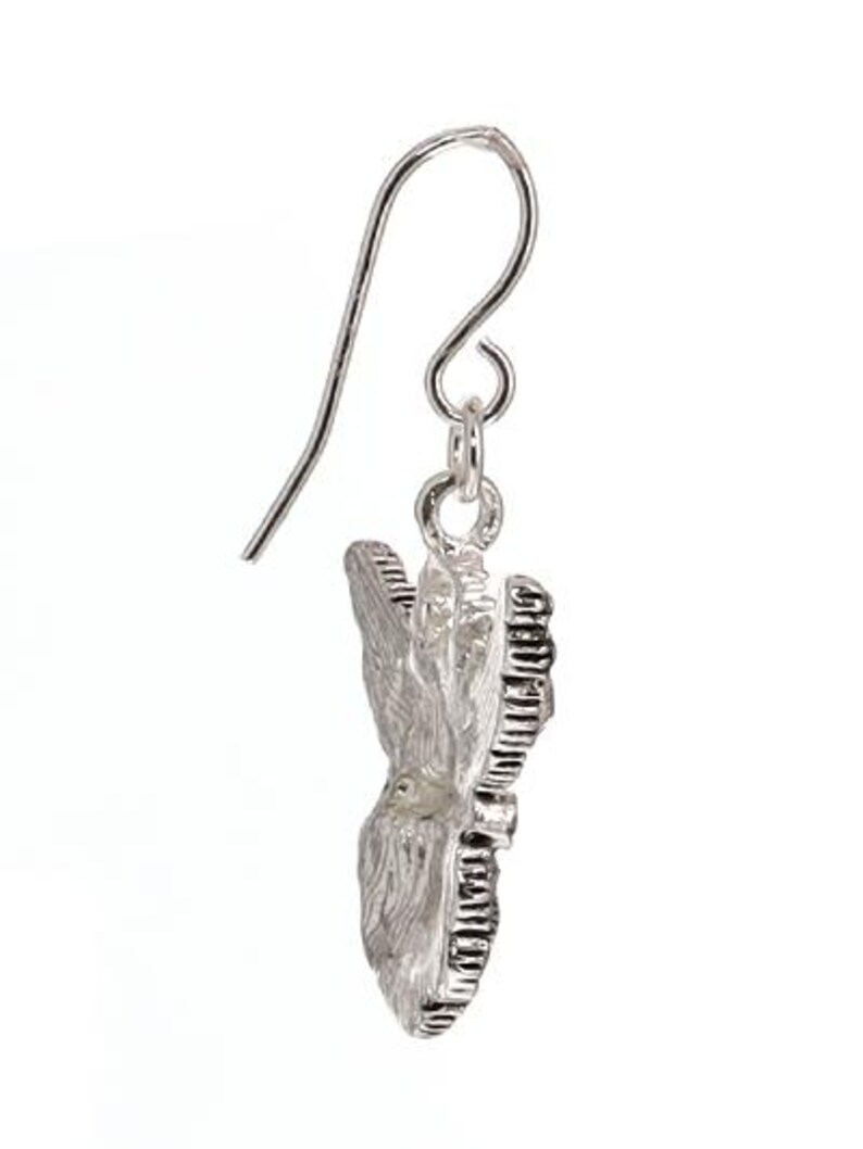 May include: Silver butterfly dangle earrings with a textured design. The earrings have a hook closure.
