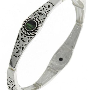 May include: Silver tone stretch bracelet with an ornate design and a green abalone shell inlay.