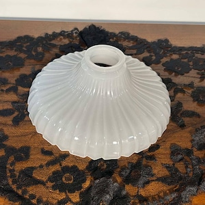 May include: White glass lampshade with a fluted design. The lampshade is round and has a wide opening at the top.