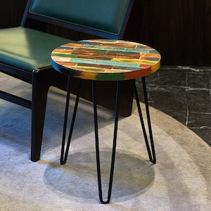 May include: A small round side table with a colorful, multi-colored, painted wood top and black hairpin legs.