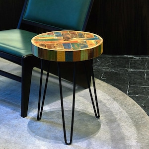 May include: A small round side table with a colorful, multi-colored wood top and black hairpin legs.