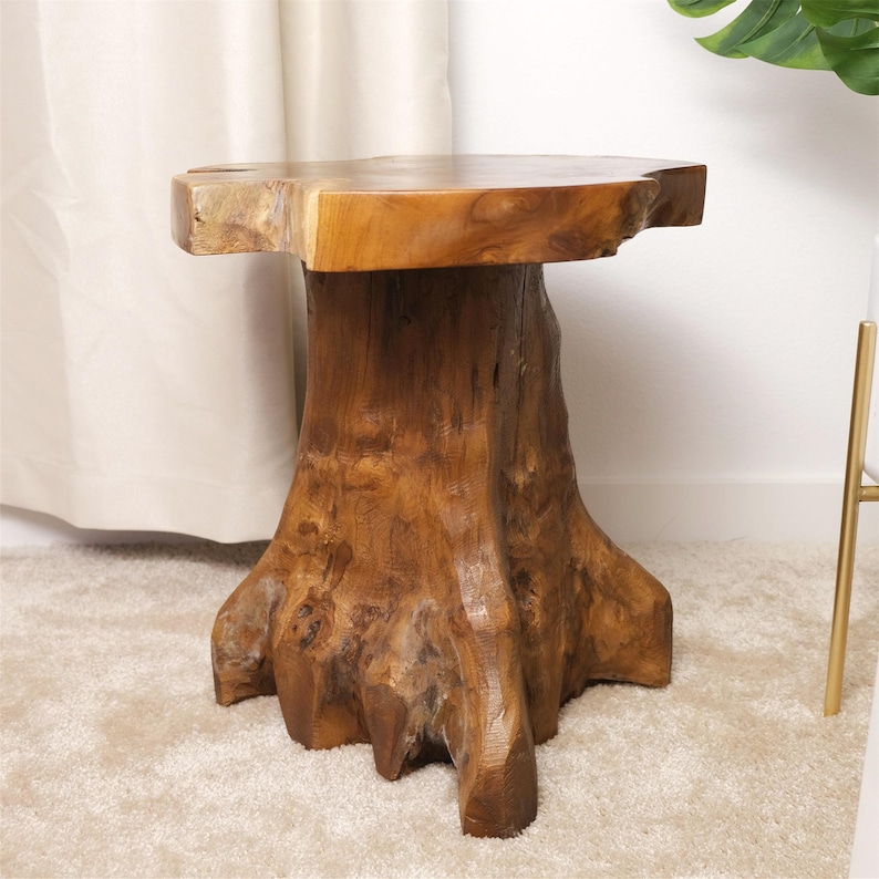 May include: A round wooden table with a natural wood finish. The table top is a thick slice of wood with a rough edge. The base of the table is a tree trunk with natural knots and branches.