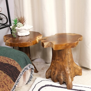 May include: Two wooden end tables made from natural tree trunks. The tables have a rustic, organic look and are perfect for adding a touch of nature to any room.