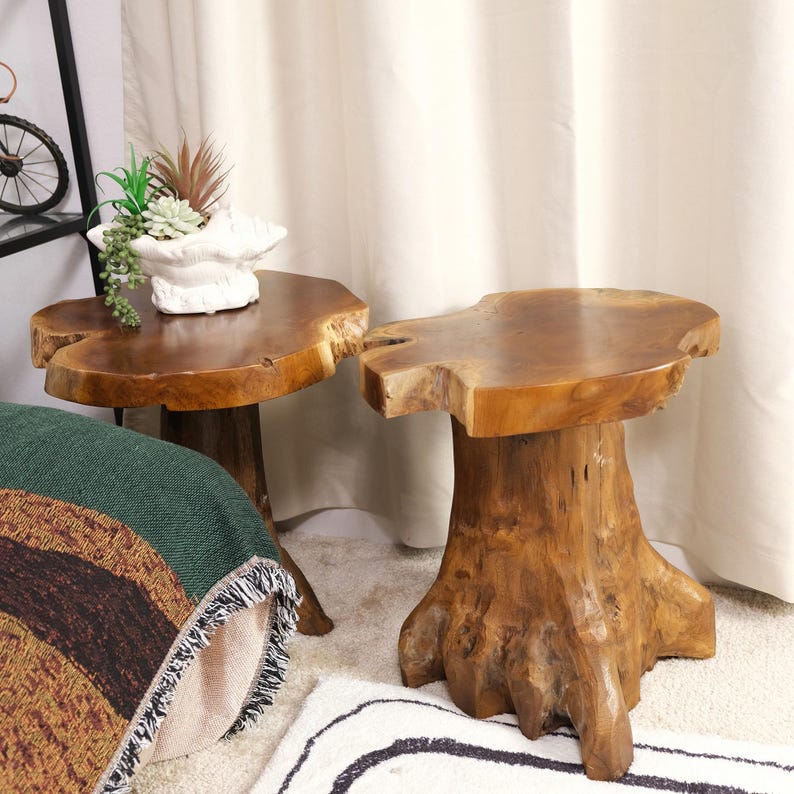 May include: Two wooden end tables made from natural tree trunks. The tables have a rustic, organic look and are perfect for adding a touch of nature to any room.