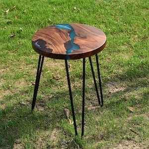 May include: A round wooden table with a blue resin inlay. The table has four black hairpin legs.