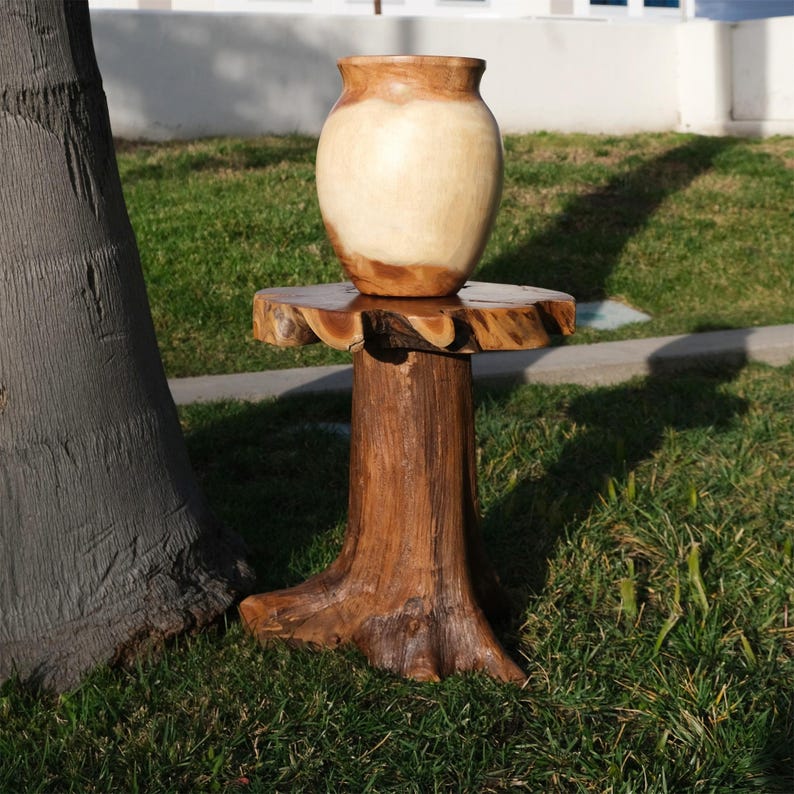 May include: A wooden table with a tree trunk base and a round top. A light brown wooden vase sits on the table.