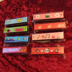 May include: A set of ten colorful harmonicas with various animal and musical note designs. Each harmonica is packaged individually in clear plastic.