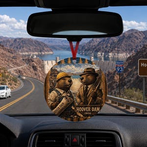 Könnte beinhalten: Ein runder Hängeschmuck mit einer Illustration von zwei Bibern, einer trägt einen gelben Bauhelm und hält einen Bauplan, der andere trägt einen Fedora und Anzug und hält eine Schaufel, mit dem Text Hoover Dam 1936 unten.