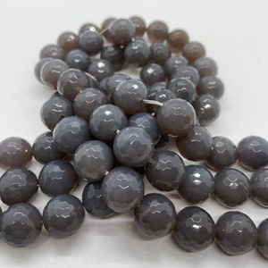 May include: A strand of grey faceted agate beads. The beads are round and have a smooth, polished finish.