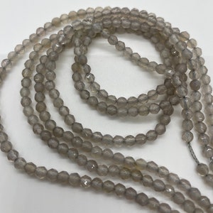 May include: Multiple strands of grey, faceted gemstone beads. The small, round beads have a subtle sparkle. The strands are arranged in layers, creating depth and texture. Suitable for jewellery making.