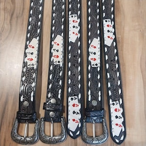 May include: Five black leather belts with ornate silver buckles. Each belt features a playing card design with the Ace of Spades, Hearts, Diamonds, and Clubs. The belts have a decorative floral pattern with white accents.