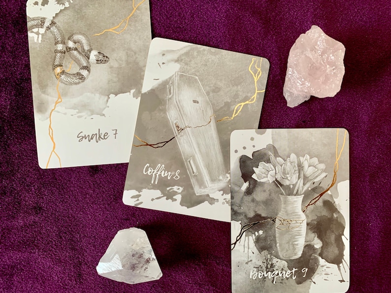 May include: Three tarot cards with black and white illustrations on a purple background. The cards are labeled "Snake 7", "Coffin 8", and "Bouqnet 9".