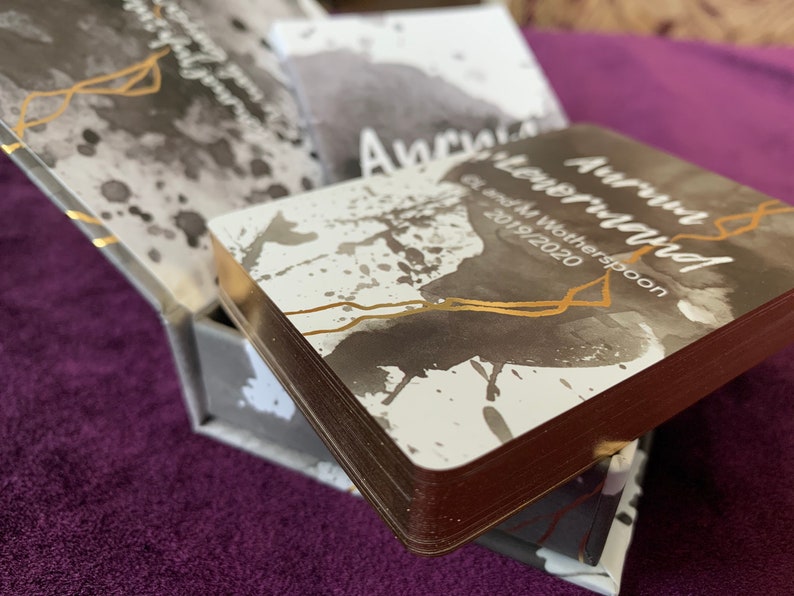 May include: A stack of cards with a gray and white watercolor design and gold accents. The top card has the text "Autumn Wonderland" and "G & M Witherspoon 2019/2020".