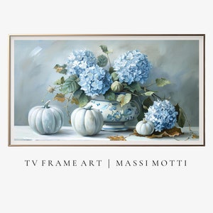 May include: A still life painting featuring a blue and white porcelain vase filled with blue hydrangeas. The vase is surrounded by three white pumpkins on a table with a light gray background. The painting is framed in a gold frame and has the text "TV FRAME ART | MASSI MOTTI" at the bottom.