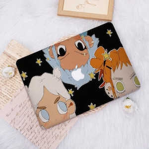 May include: Black laptop case featuring a cartoon illustration of three stylized characters with large eyes and star accents. The case has a black background with a white Apple logo.