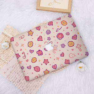 May include: A laptop hard shell case featuring a beige background with a repeating pattern of small, colorful cartoon icons including smiling stars, hearts, clouds, and crosses in shades of pink, yellow, orange, and purple, with a central apple logo cutout.