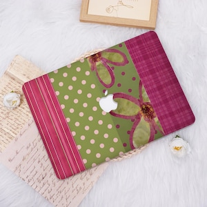 May include: A laptop skin featuring a vertical design with a magenta striped section, a sage green section with light pink polka dots, a central sage green panel with a large magenta flower illustration, and a magenta plaid section on the right.