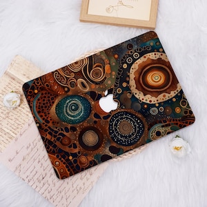 May include: A laptop cover featuring a complex abstract pattern of concentric circles and swirling lines in shades of brown, deep blue, orange, and gold. The design incorporates a central cutout for the Apple logo, creating a layered visual effect.