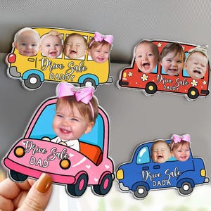 May include: A collection of car magnets featuring smiling babies in colorful vehicles. The magnets include a yellow school bus, a red car, a pink car, and a blue car, each with the text "Drive Safe" and a variation of "Daddy" or "Dada".