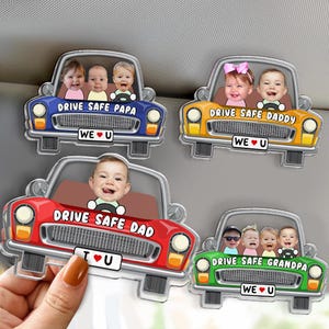 May include: Four car-shaped acrylic magnets with personalized baby photos. Each car is a different color: blue, yellow, red, and green. Text on each magnet reads "Drive Safe" followed by "Papa", "Daddy", "Dad", or "Grandpa". Each magnet has the text "WE U".