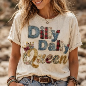 Könnte beinhalten: Cremefarbenes, abgenutztes T-Shirt mit dem Text "Dilly Dally Queen" in Patchwork-Buchstaben. Die Buchstaben sind aus Denim, karierten und floralen Mustern, mit einer Krone über dem Wort "Queen". Das Shirt hat einen Rundhalsausschnitt und kurze Ärmel.
