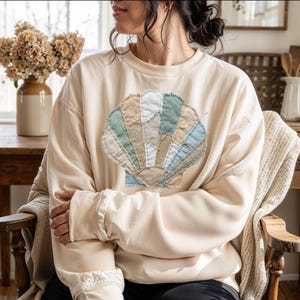 以下が含まれることがあります： クリーム色、ライトグレー、ダークグレーの3色の、まだら模様のマット仕上げのセラミックマグのセット。各マグはシンプルでミニマルなデザインで、丸みを帯びたハンドルが付いています。