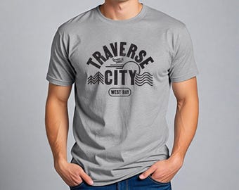 May include: A gray t-shirt with a black graphic print that says "Traverse City" with a small airplane and a sun graphic. The text "West Bay" is printed below the graphic.