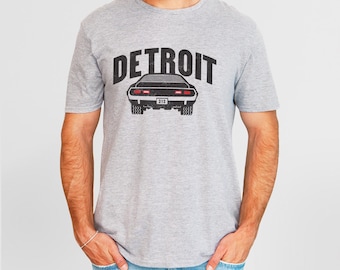 May include: A heather grey t-shirt with a black graphic of a classic car and the word "DETROIT" printed on the front.