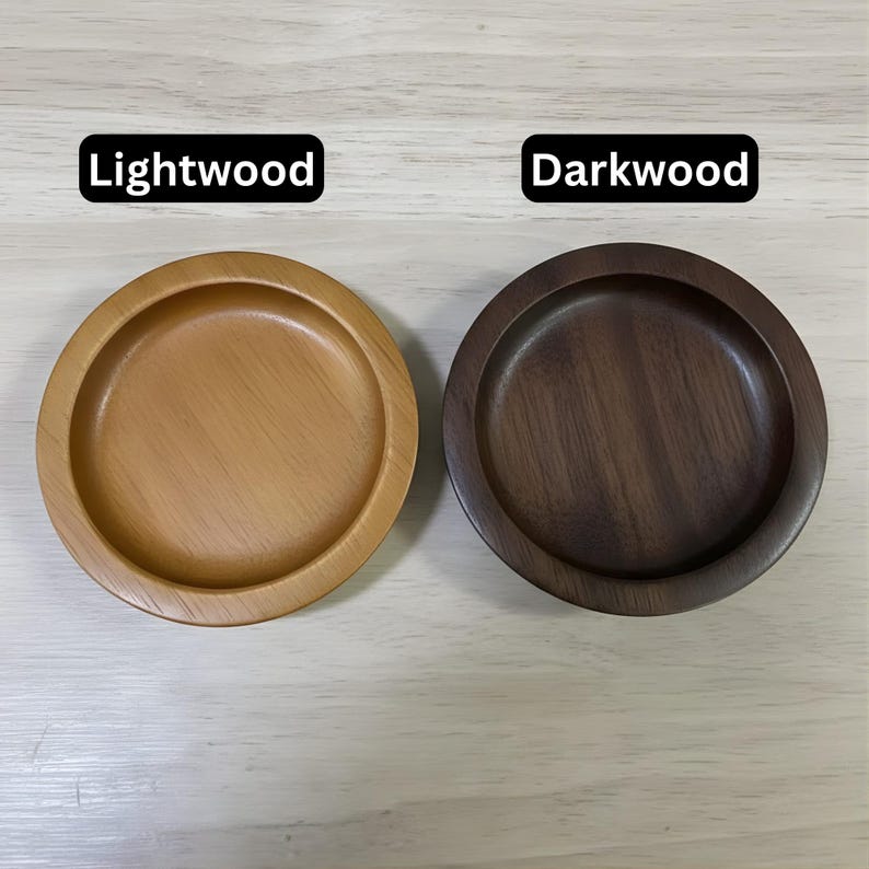 May include: Two wooden coasters, one light and one dark, are displayed side-by-side. The light coaster is a warm, natural wood tone, while the dark coaster is a rich, deep brown. The text "Lightwood" and "Darkwood" are above each coaster.