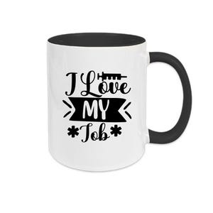 Op de afbeelding: Witte keramische mok met een zwarte binnenkant en handvat. De mok heeft de tekst "I Love MY Job" in het zwart, met een spuitgrafiek boven het woord "Love" en sterretjes rond "Job".