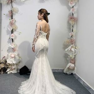 Elegant and modern ivory long sleeve mermaid wedding dress with sparkling beads and a classic corset design that flatters the figure