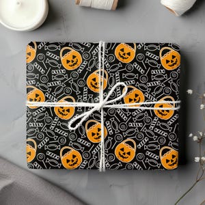 Op de afbeelding: Zwart en oranje Halloween-cadeaupapier met een herhalend patroon van jack-o'-lantern-emmers en snoep.