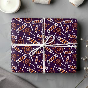 Op de afbeelding: Paars cadeaupapier met een herhalend patroon van oranje en witte snoepstokken, oranje en witte lolly's en oranje swirl snoepjes.